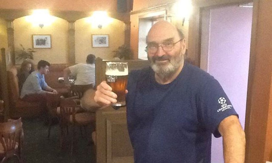 Duncan, an older gentleman in a pub, toasts the photographer with a pint of lager.