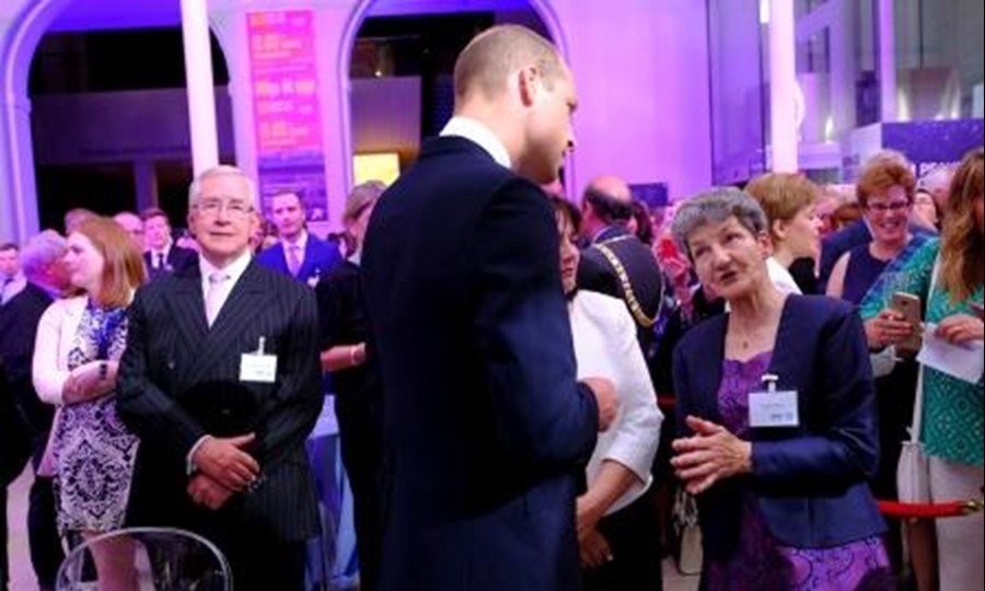 In a busy room, Donor Carer Evelyn chats to HRH The Earl of Strathearn. 
