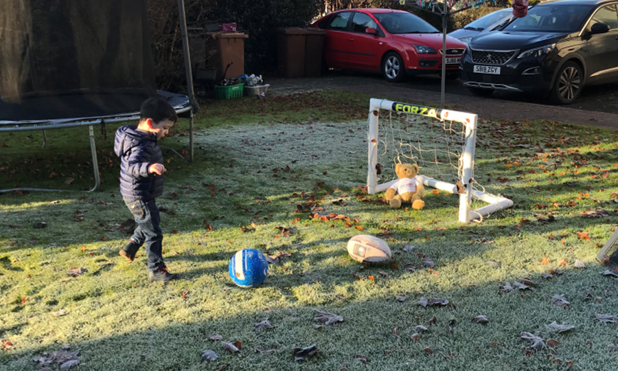Iain plays football outside in the garden.  