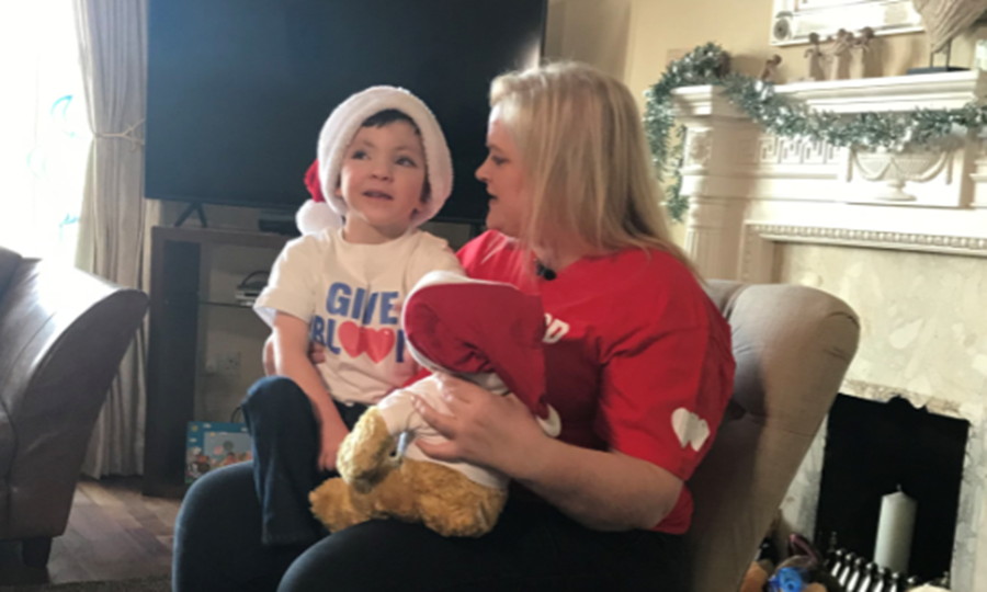 Iain sits on Mum Nicola's knee. Both are wearing Give Blood t-shirts. 