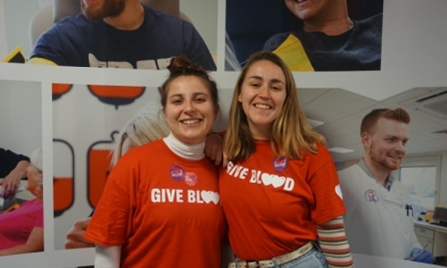 Martha and Hanna smiling wearing 'give blood' t-shirts and 'Give Blood 4 Good' stickers