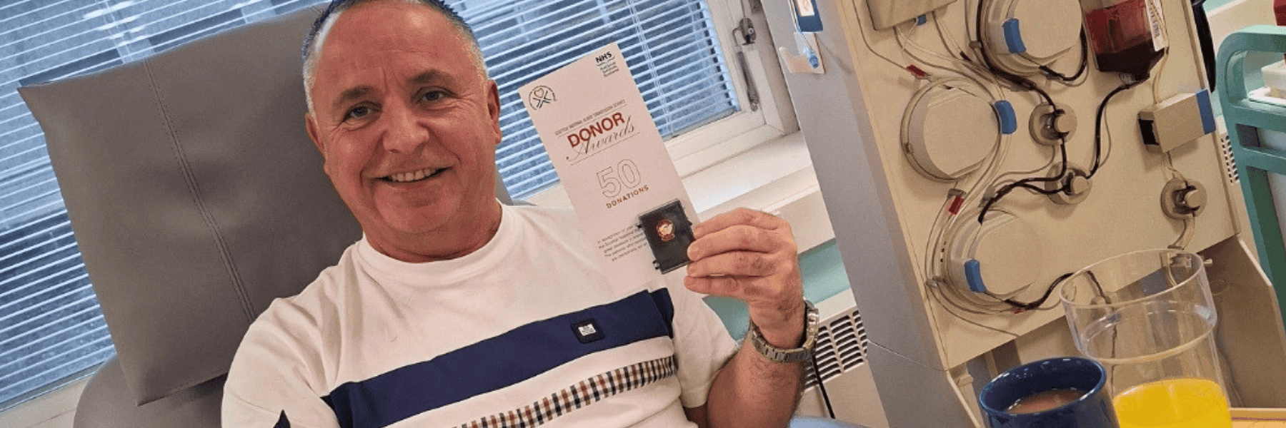 Pete holds up his 50th donation certificate while donating plasma at Dundee Donor Centre