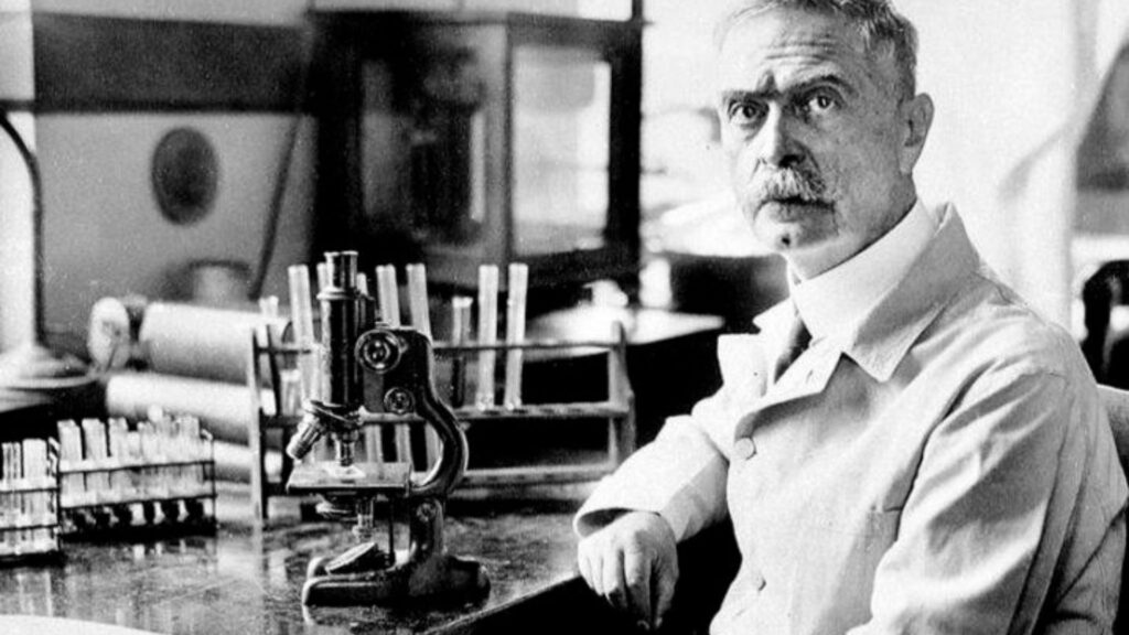 Photograph of Karl Landsteiner sitting in his laboratory, using miscroscope